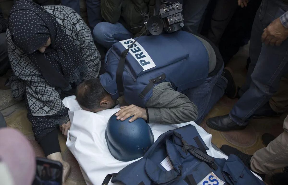 Fotografía de archivo del 16 de diciembre de 2023 donde se muestra a amigos y familiares del periodista palestino Samer Abu Daqqa, camarógrafo muerto durante ataques aéreos israelíes, llorando al lado su cuerpo en el sur de la Franja de Gaza. EFE/Haitham Imad