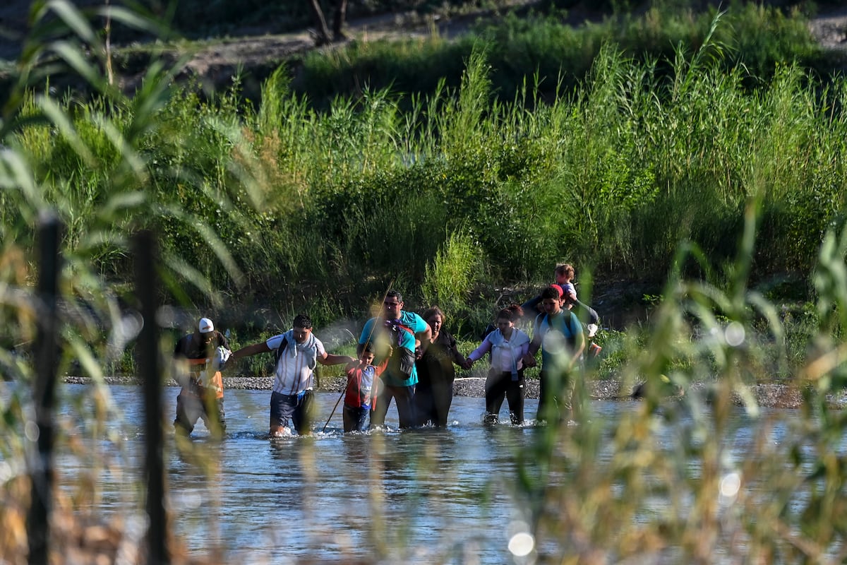 Una familia migrante de Venezuela cruzando ilegalmente el Río Grande en Eagle Pass, Texas, en la frontera con México el 30 de junio de 2022 (Foto: AFP)