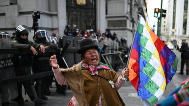 Una mujer indígena que sostiene una bandera Wiphala hace un gesto frente a la policía antidisturbios durante una protesta contra el gobierno del presidente Rodrigo Paz en el Día de la Madre en La Paz, el 27 de mayo de 2026. (Marvin RECINOS / AFP)