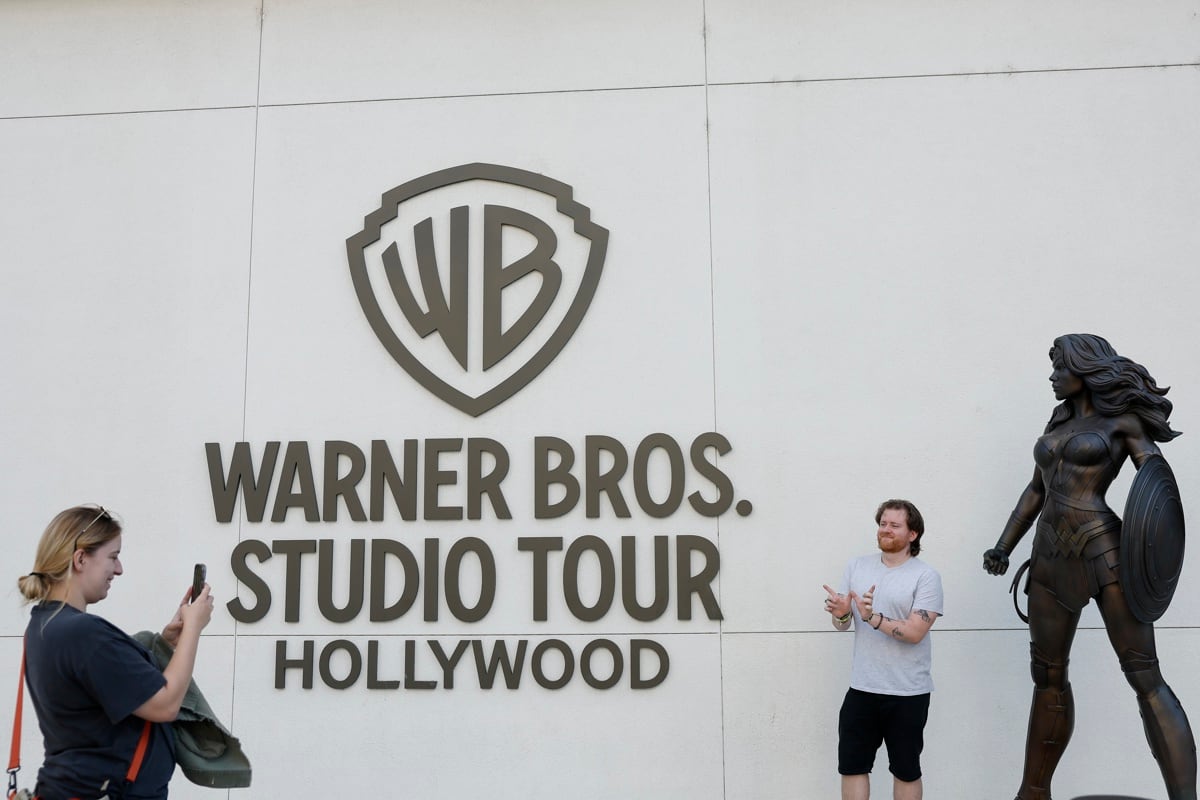 Fotografía de archivo del 21 de octubre de 2025 que muestra a personas posando frente al lugar donde se realiza el recorrido por los estudios Warner Bros. de Burbank, California (EE.UU.). La junta de accionistas de la empresa Warner Bros. Discovery (WBD) aprobó este jueves fusionarse con Paramount Skydance, según anunció la primera compañía en un comunicado. EFE/EPA/CAROLINE BREHMAN /ARCHIVO