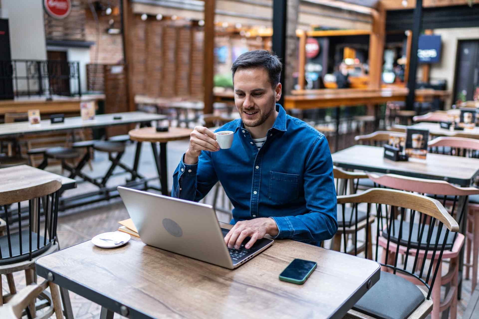Un hombre disfruta de un café mientras trabaja en su computadora portátil en una cafetería de la ciudad. (iStock)
