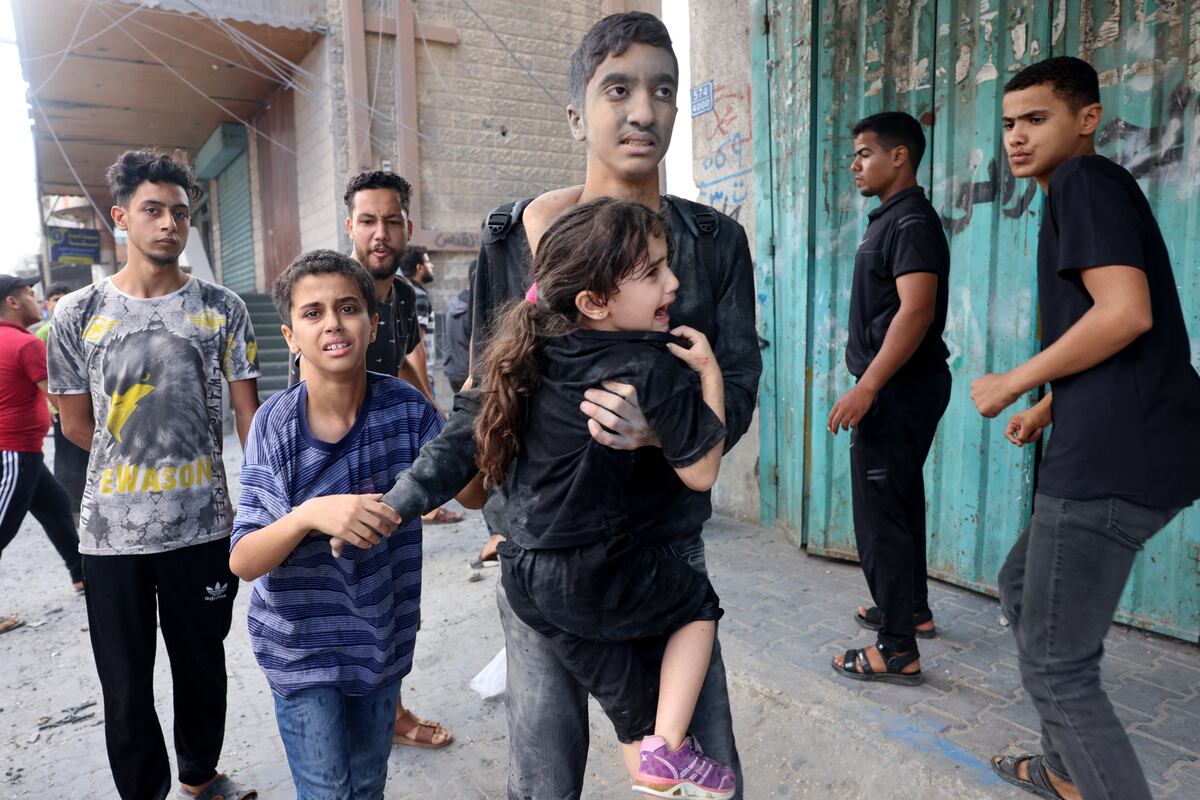 Un joven carga a una niña después de un ataque israelí, mientras las batallas entre Israel y el movimiento Hamás continúan por sexto día consecutivo en Rafah, en el sur de la Franja de Gaza. (Foto de SAID KHATIB / AFP).