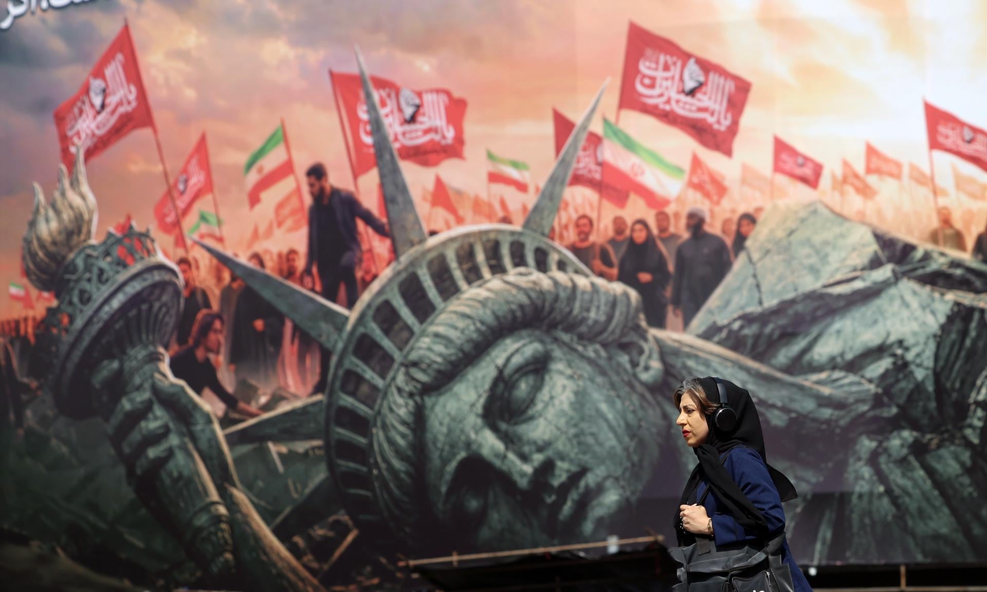 Una mujer iraní camina junto a una valla publicitaria antiestadounidense en la plaza Enghelab, en el centro de Teherán, Irán, el 13 de agosto de 2026. (EFE/EPA/ABEDIN TAHERKENAREH).