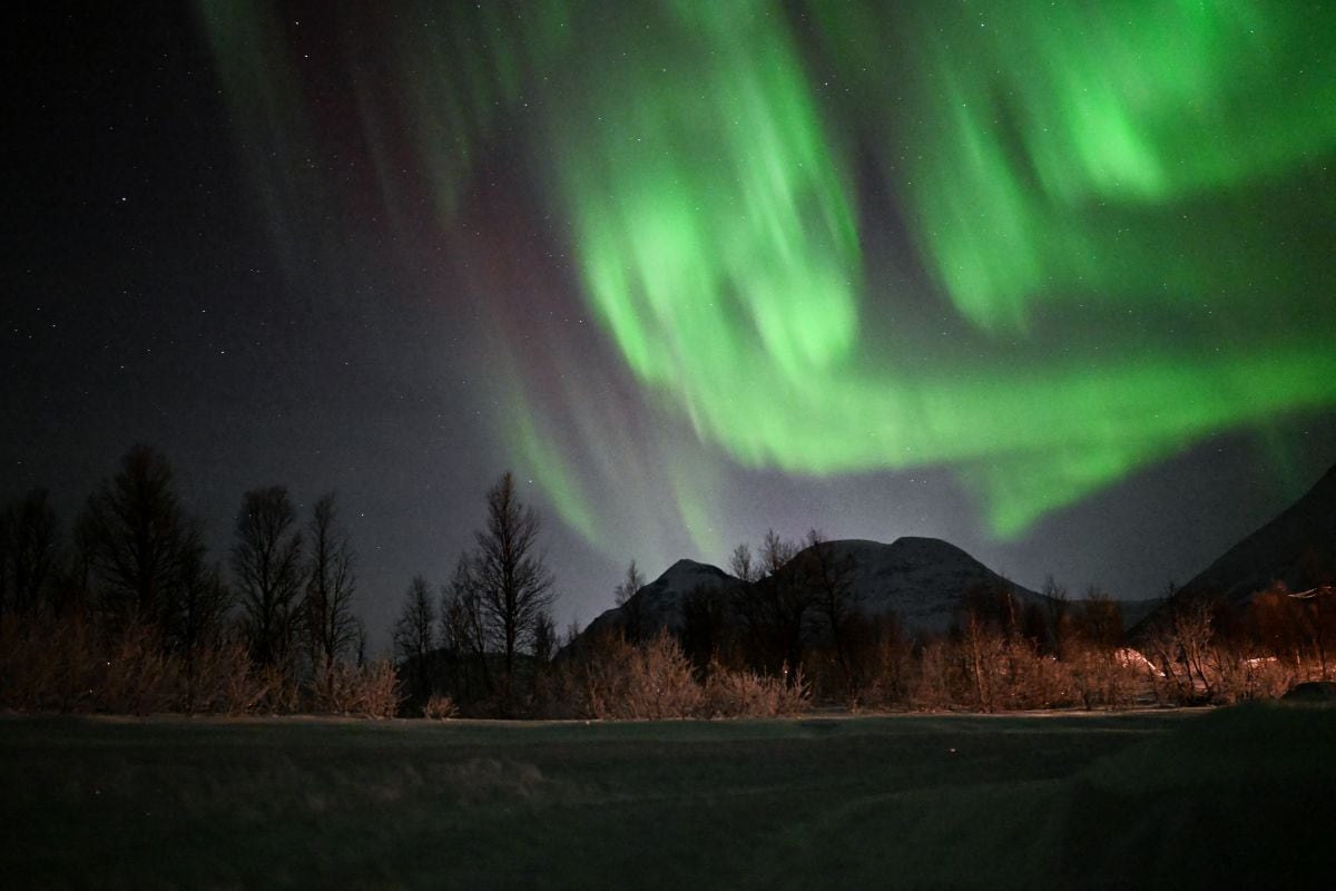 La aurora boreal ilumina el cielo sobre un campamento sami en las afueras de la aldea de Breivikeidet, cerca de Tromso, Noruega, más allá del Círculo Polar Ártico, el 1 de enero de 2024 (Foto: Sergei Gapon / AFP)