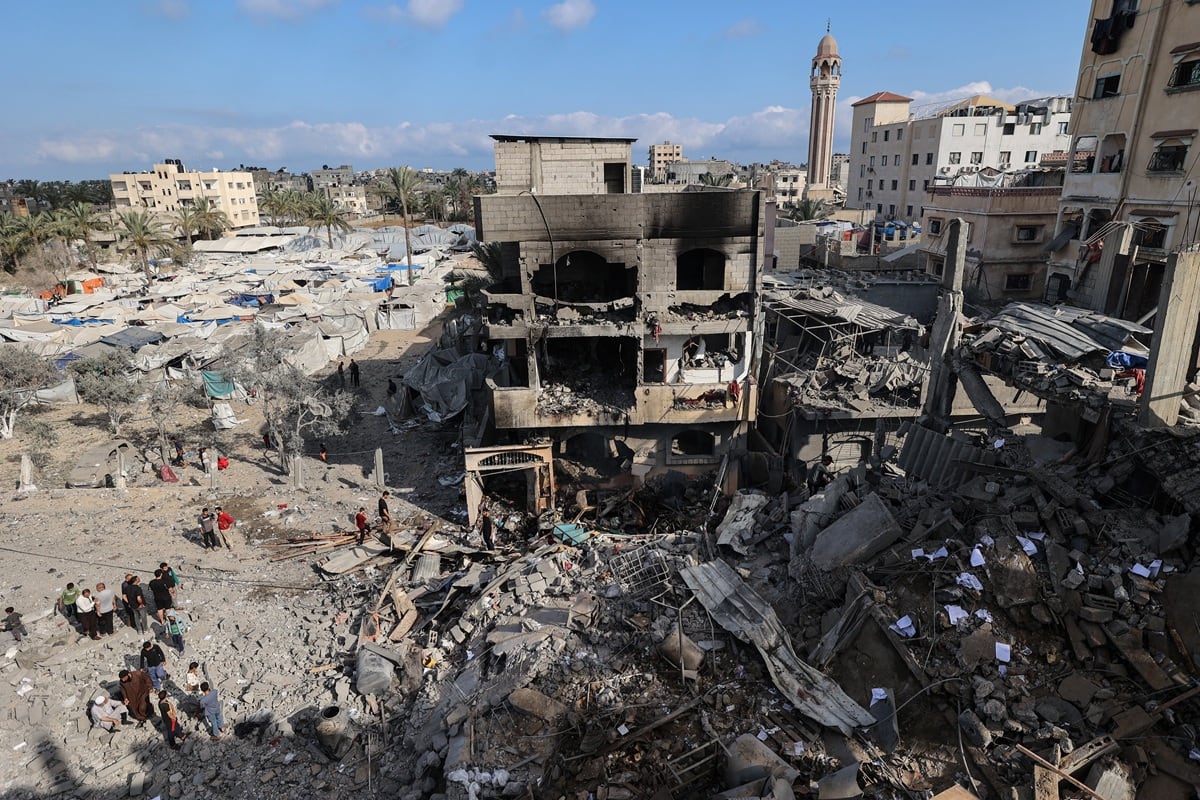 Palestinos inspeccionan los escombros en el lugar donde se encontraba un edificio residencial atacado durante la noche por un ataque israelí, en Deir el-Balah, en el centro de la Franja de Gaza. (Eyad Baba / AFP)
