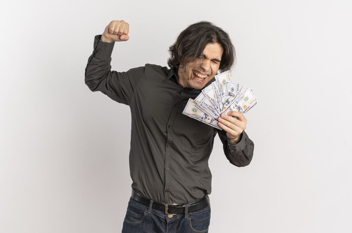 Un joven celebra con varios billetes de 100 dólares en mano. (Foto: Freepik)