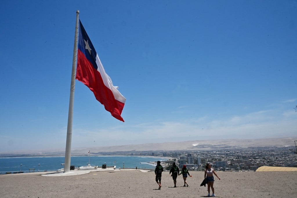 Turistas caminan hacia la bandera nacional chilena en el Morro de Arica, en Arica, Chile, en la frontera con Perú, el 30 de noviembre de 2025. (Foto de RODRIGO ARANGUA / AFP)