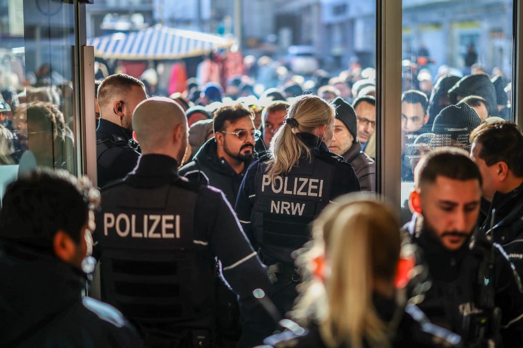 Policías y clientes bancarios preocupados se encuentran frente a una sucursal del banco Sparkasse en Gelsenkirchen, oeste de Alemania, el 30 de diciembre de 2025, tras un robo. Según informes de prensa, los clientes se congregaron frente al banco para averiguar qué había pasado con sus objetos de valor, después de que uno o varios desconocidos perforaran la bóveda del banco y entraran a robar durante las vacaciones de Navidad. (Foto de Christoph Reichwein / dpa / AFP)