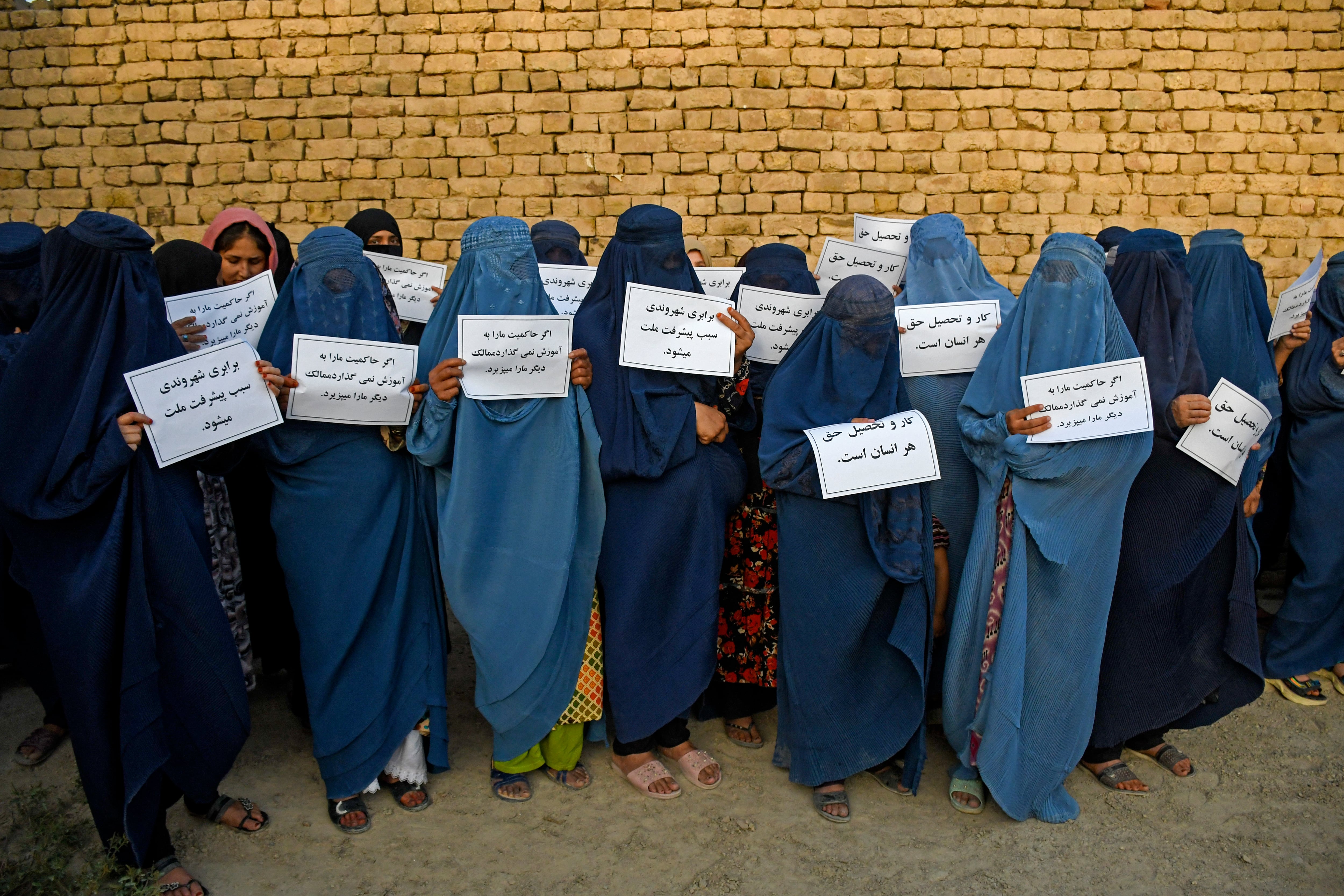 Mujeres afganas vestidas con burka sostienen pancartas mientras protestan por su derecho a la educación. Foto: ATEF ARYAN / AFP