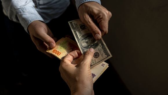 Un cambista sostiene un billete de cien dólares estadounidenses y billetes de 1,000 pesos en Buenos Aires, Argentina, el jueves 27 de abril de 2023.