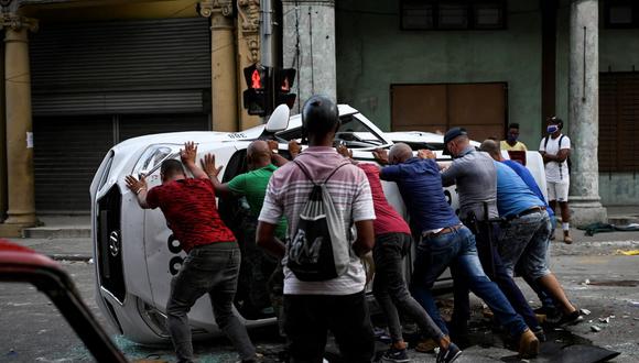 La gente empuja un automóvil volcado en la calle durante una manifestación contra el presidente cubano Miguel Díaz-Canel en La Habana, Cuba, el 11 de julio de 2021. (YAMIL LAGE / AFP).