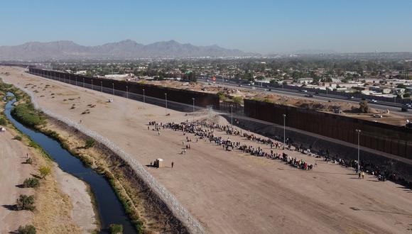Migrantes esperan a orillas del Río Grande para ser procesados por la Patrulla Fronteriza Sector El Paso, Texas, después de cruzar desde Ciudad Juárez, México, el 10 de mayo de 2023. (Foto de HERIKA MARTINEZ / AFP)