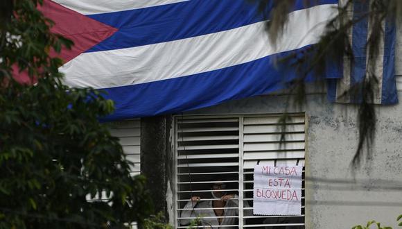 Yunior García Aguilera, dramaturgo y uno de los organizadores de una marcha de protesta el 15 de noviembre, aparece junto a un letrero que dice "Mi casa está bloqueada", que colgó en una ventana de su domicilio en La Habana, Cuba, el domingo 14 de noviembre de 2021. (Foto: AP).