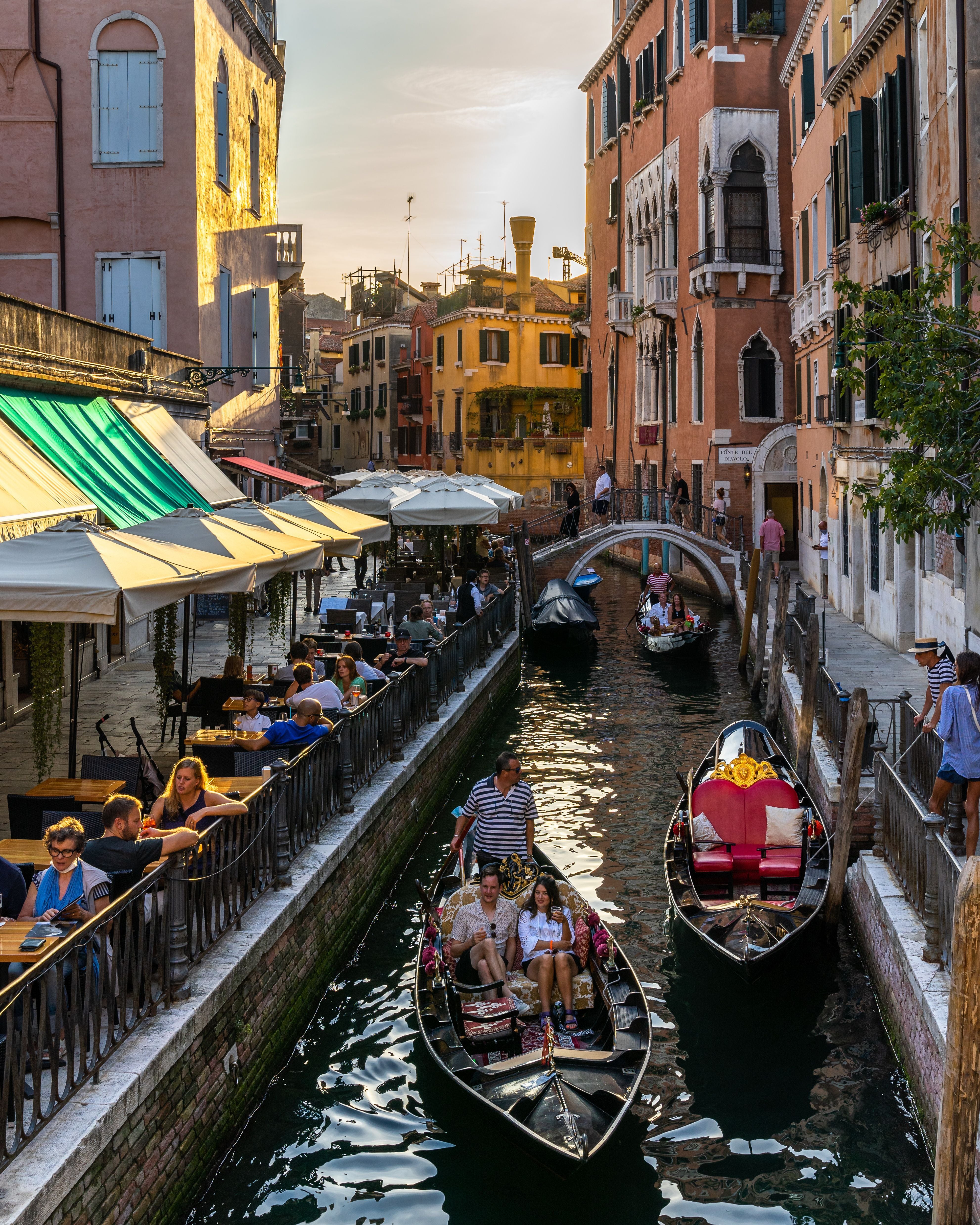 Venice, Italy, Sept. 11, 2020 – Picturesque Venice canal with gondolas and tourists on the right enjoying the sunset in a cocktail bar