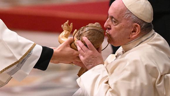 El Papa Francisco besa una figura del niño Jesús mientras asiste a la misa de Nochebuena en la Basílica de San Pedro en el Vaticano el 24 de diciembre de 2022. (Foto de Andreas SOLARO / AFP)