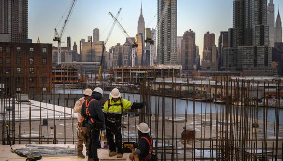Una vista general muestra a los trabajadores de la construcción de pie ante el horizonte de Manhattan y el Empire State Building, en Brooklyn el 24 de enero de 2023. (Foto de Ed Jones / AFP)