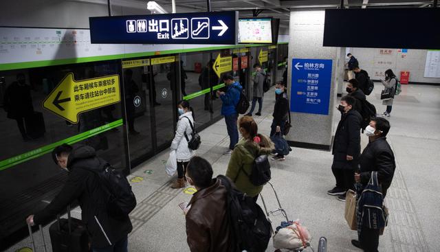 Los pasajeros con máscaras protectoras esperan para tomar un tren subterráneo en Wuhan. La ciudad reanudó parcialmente los servicios de transporte. (EFE).