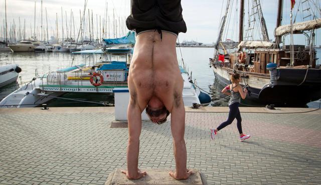 Un hombre se ejercita mientras una mujer pasa corriendo por atrás en Palma de Mallorca, España, el 2 de mayo de 2020. (JAIME REINA / AFP).