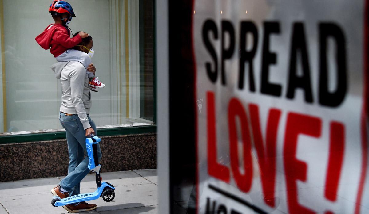 Un hombre que usa una máscara facial lleva a un niño que también usa una máscara facial sobre sus hombros en medio de la pandemia de coronavirus en Washington, DC, Estados Unidos. (Foto: AFP/Olivier DOULIERY)