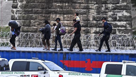 Inmigrantes caminan sobre los contenedores después de cruzar la frontera desde México (Foto de CHANDAN KHANNA / AFP)