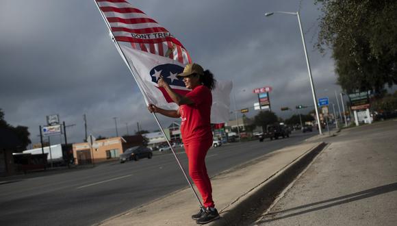La partidaria republicana Dolly Schultz sostiene banderas afuera de un lugar de votación en el Centro Cívico SSGT Willie de Leon al comienzo de la votación en Uvalde, Texas, el 8 de noviembre de 2022. (Foto de Mark Felix / AFP)
