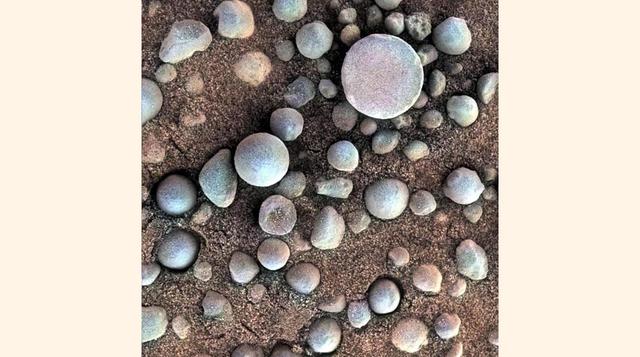 ´Superficie marciana´ que muestra esférulas en la superficie del Planeta Rojo. La sobra corresponde al brazo del ´Opportunity´.
