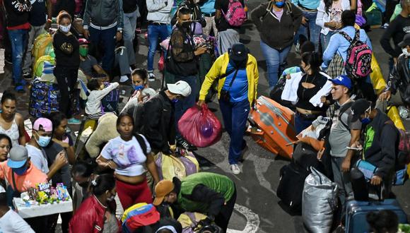 Migrantes venezolanos llevan su equipaje antes de abordar un autobús para regresar voluntariamente a su país desde Cali, Colombia. (AFP / Luis ROBAYO).